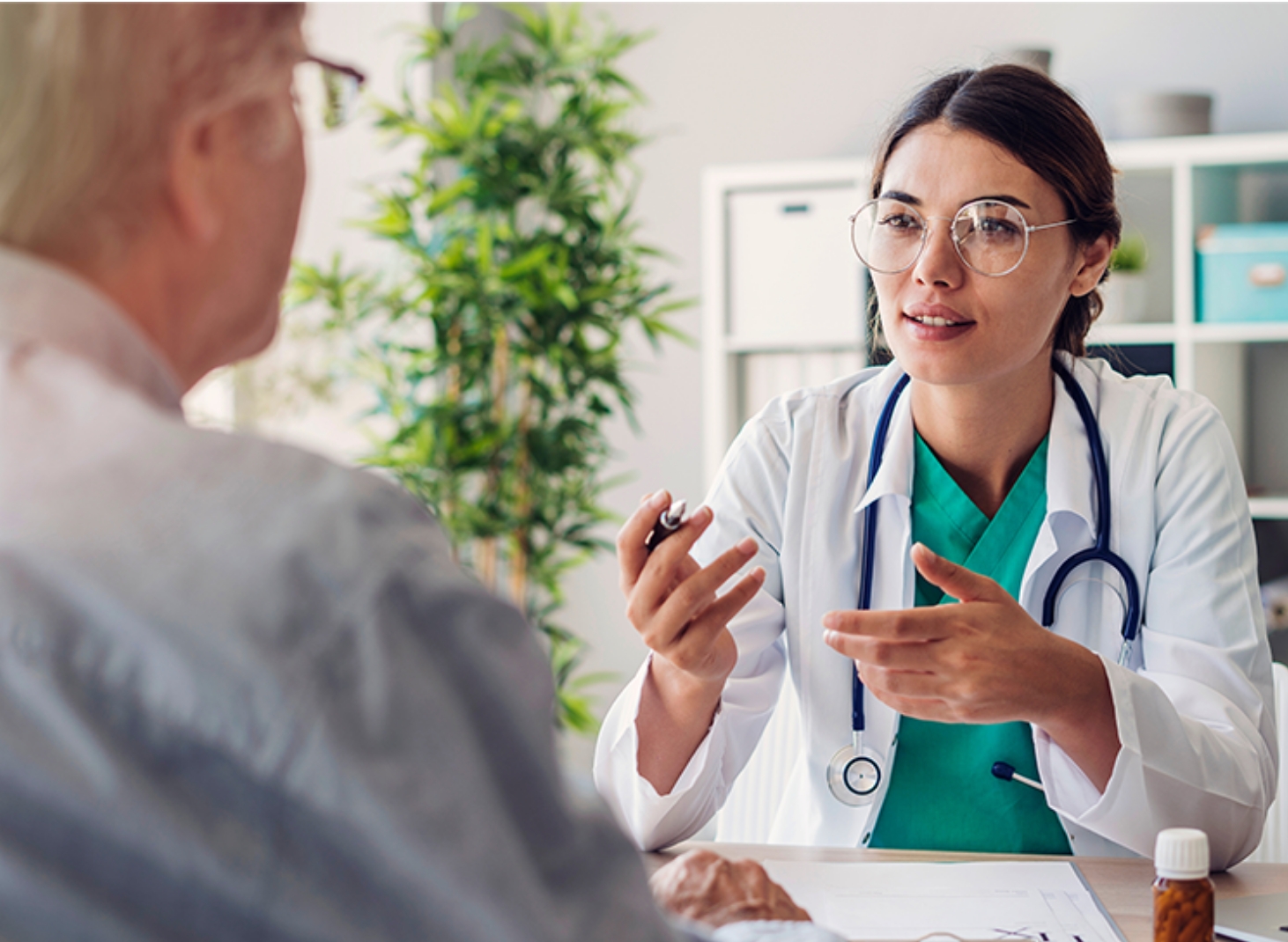 A doctor and patient sitting at a desk. The doctor is telling something to the patient.